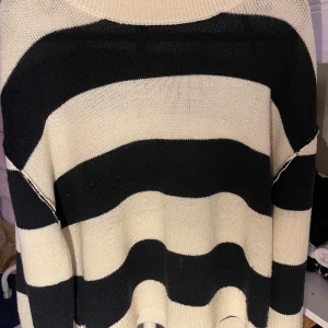 Randig stickad tröja från H&M Divided - Säljer en oversized stickad tröja från H&M Divided i storlek L. Tröjan har breda svarta och vita ränder, rund halsringning och långa ärmar. Perfekt för lager-på-lager och chill dagar. Supermjuk och skön att ha på sig.