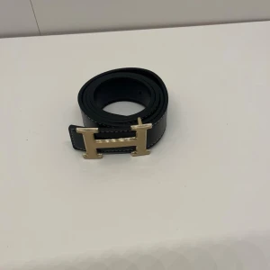 Bälte - Ett svart bälte med guldig H, den är helt ny och är i 105 cm. Pris kan diskuteras och skriv om du har några frågor. 