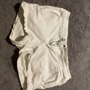 Vita shorts från Mohito Basic - Snygga vita shorts från Mohito Basic med klassisk passform. De har dragkedja och knapp framtill, fickor på sidorna och bak samt bälteshällor. Perfekta för varma dagar och enkla att matcha med allt. Materialet känns mjukt och bekvämt. Storlek 36 men passar nog M också.