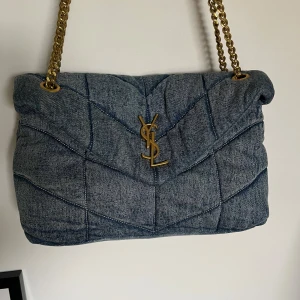 YSL väska i jeanstyg - Supersnygg väska i jeanstyg från YSL. Köpt här på plick för några år sedan med dustbag samt medföljande box men tyvärr har jag tappat bort både lådan och dustbagen. Då jag ej har kvitto kan jag ej garantera äktheten och därav priset jag säljer den för🥰  Använd men skickat är fortfarande som nytt, inga fläckar eller skador. Bara lite nopprigt på mockan vid axelremmen.