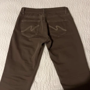 Low Waist Bootcut Stitch Jeans Nelly - Byxorna är bruna i storlek 40. Dem är ALDRIG använda, jag har alltid tyckt att dem är för långa på mig som är 165 cm. Så, jag klippte dem och längden är perfekt på dem som är 166 cm och neråt🥰🫶🏻 byxorna är väldigt stretchiga med. Pris kan diskuteras🫶🏻Kan även skicka med de som jag klippt bort vid fötterna, om man skulle vilja det! 