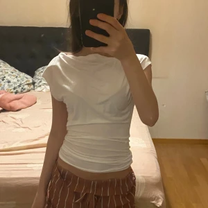 Vit topp  - Säljer en vit topp från Lager 157 i storlek XS. Toppen har en snygg draperad effekt över axlarna och midjan, med korta ärmar och en fin passform. Perfekt för dig som gillar stilrena och enkla plagg. 