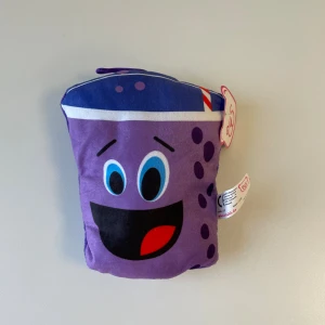 Mjukis dricka kramdjur  - En mjukiskudde med ett glatt ansikte, lila färg och mått på cirka 18x14 cm. Produkten är helt ny. 