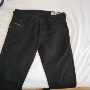 Svarta Diesel jeans W29 L30 - Snygga svarta jeans från Diesel med klassisk femficksdesign och raka ben. Jeansen har en diskret Diesel-logga på bakfickan och är tillverkade i mjukt jeansmaterial med en mörk ton. Passar dig som gillar stilrena och tidlösa byxor. Mycket bra skick 
