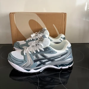 Asics Gel-1130 sneakers i silver och blå - Snygga Asics Gel-1130 sneakers i en fräsch mix av silver, ljusblått och vitt. Ovandel i mesh och syntet med coola detaljer och klassisk Asics-logga på sidan. Skorna har snörning och en chunky, vit sula med svarta och grå inslag. Perfekta för dig som gillar sportig stil.