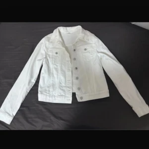 Vit jeansjacka med silverknappar - Vit jeansjacka med klassisk krage och silverfärgade knappar framtill