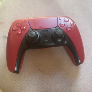 PlayStation 5 DualSense Wireless Controller Cosmic Red - Snygg PlayStation 5 DualSense-kontroll i Cosmic Red. Trådlös, med adaptiva triggers och haptisk feedback. Kontrollen är i gott skick med endast mindre tecken på användning. Perfekt för dig som vill ha en extra eller byta ut din nuvarande PS5-kontroll.