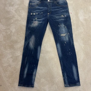 Dsquared2 jeans - Snygga blå jeans från Dsquared2 i klassisk rak passform. Jeansen har coola slitningar, patchade detaljer och blekta partier som ger en edgy vibe. Tillverkade i Italien av jeansmaterial med fem fickor och knappgylf. Perfekt för dig som gillar streetstyle. Äkta!