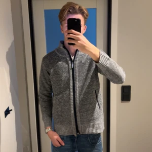 Grå stickad kofta/cardigan med dragkedja - Säljer en grå stickad kofta/cardigan som är varm och även fodrad.  Det är storlek M men passar bättre S. Jag säljer denna produkt då jag fick fel på leveransen och fick fel produkt och har varit problematiskt med returen så jag väljer att sälja den här istället. Den är lite liten på mig och jag är 186 lång.