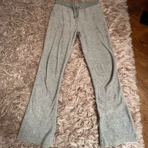 Grå Juicy Couture byxor  - Gråa byxor från Juicy Couture med glittrande JC-logo på ena benet. Byxorna har snöre i midjan och två bakfickor. Skriv till mig om ni har några frågor eller är intresserade 