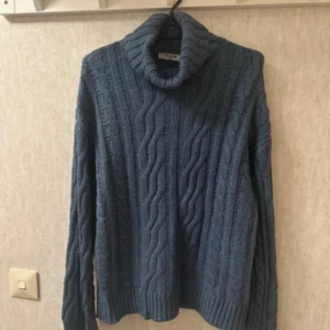 Blå polotröja från NA-KD - Säljer en blå polotröja från NA-KD i storlek XS. Tröjan är stickad med grovt kabelmönster och har en hög, mysig polokrage. Långärmad och med ribbade muddar vid ärmslut och nederkant. Perfekt för kyliga dagar och snygg att styla med jeans.