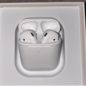 AirPods 2 - Säljer ett par Apple AirPods 2 i originalförpackning. Hörlurarna och laddningsfodralet är i nyskick, utan synligt slitage eller repor. Perfekt för trådlös musik och samtal med lång batteritid. Levereras komplett med box och tillbehör.