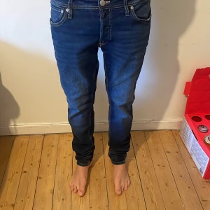 Replay Anbass mörkblå jeans - Säljer ett par Replay Anbass jeans i mörkblå tvätt med snygga slitningar och klassiska fem fickor. Jeansen har smal passform och raka ben, med detaljerade sömmar och Replay-logga på bakfickan. Perfekt för dig som gillar stilrena och moderna jeans.