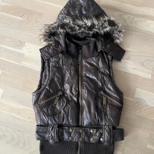 Brun väst med huva och päls - Snygg brun väst med huva med fuskpäls och bred ribbad mudd nedtill. 