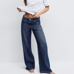 Low wide jeans från gina tricot - Säljer ett par blå jeans från Perfect Jeans i modell med breda ben och låg midja. Klassisk femficksdesign och snygg tvättad denim. Perfekta för dig som gillar en avslappnad och trendig look.