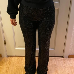 Svarta paljettbyxor - Snygga svarta byxor med glittriga paljetter över hela tyget. Utsvängd i slutet och sitter högt i midjan. Perfekta för dig som vill sticka ut med lite extra bling. Perfekt för festliga tider men även nyår mm. Passar för storlek XS och S😊