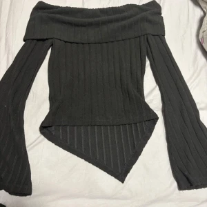 Svart offshoulder topp från SHEIN - Säljer en svart ribbad offshoulder topp från SHEIN i storlek S. Toppen har långa vida ärmar och en spetsig nederkant framtill för en edgy look. Perfekt för dig som gillar trendiga och unika plagg.(aldrig använt, hann aldrig komma till användning) priset kan diskuteras.