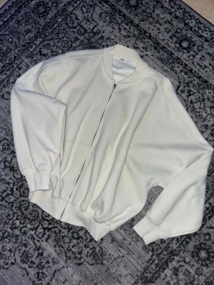 Bomberjacka från Zara - Säljer en crémefärgad bomberjacka från Zara med ribbad krage och muddar. Den är i M men sitter som S. Jackan har en rak passform, dragkedja framtill och är tillverkad i mjuk bomull. Perfekt för dig som gillar minimalistisk och clean stil.