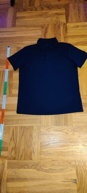 Mörkblå Peak Performance piké - Snygg mörkblå pikétröja från Peak Performance med klassisk krage och tre knappar framtill. Materialet är mjukt och känns sportigt, perfekt för dig som gillar stilren design. Diskret logga på bröstet ger en cool touch. Passformen är normal och ärmarna är korta. Ny kostar ca 500kr.