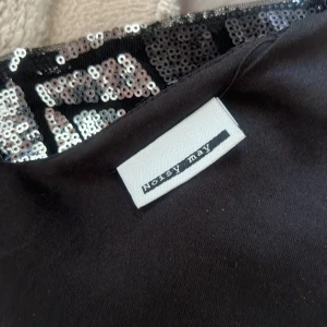 Glittrig festtopp från Noisy May - Säljer en glittrig svart och silver linnetopp från Noisy May med geometriskt mönster av paljetter. Toppen har smala axelband och v-ringning, perfekt för dig som vill sticka ut. Materialet är syntet och toppen är croppad i modellen. Köpte den på plick men säljer för att den ej satt bra på mig ❤️