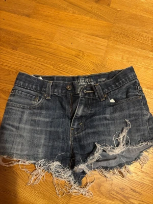 Blå Levi's Signature jeansshorts - Snygga blå jeansshorts från Levi's Signature med fransig och sliten kant för en cool vibe. Klassisk femficksmodell, normal passform och midwaist. Perfekta för sommarens alla äventyr!