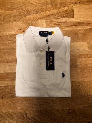 Polo Ralph Lauren Slim Fit Piké – Vit - Säljer en Polo Ralph Lauren Slim Fit piké i klassisk vit färg. Hög kvalitet och perfekt passform. Ny – endast uppackad för bilder. Tag kvar. Pris kan diskuteras så klart