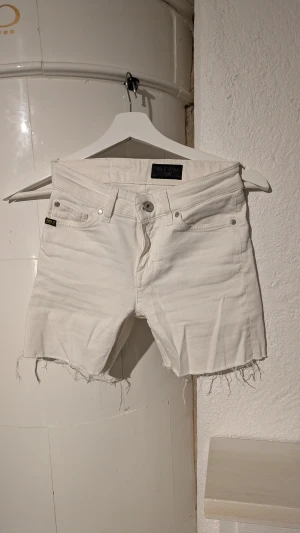 Vita jeansshorts från Tiger of Sweden - Snygga vita jeansshorts från Tiger of Sweden med råa, fransiga kanter och klassisk femficksdesign. Shortsen har knapp och dragkedja framtill samt en cool, lite loose passform. Perfekta för sommarens alla äventyr!