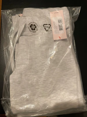 Grå mjukisbyxor från Nelly XS - Supermysiga gråmelerade sweatpants från Nelly i modellen Cozy Chill. Byxorna har hög midja, snörning i midjan och raka ben med loose passform. Perfekta för chill dagar och har en mjuk bomullskänsla som gör dem extra sköna.