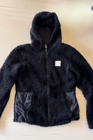 Kingsland teddy XS  - Mörkblå teddyfleece ifrån Kingsland. Otroligt varm och mysig tröja! Med luva, logga på bröstet plus ländryggen, fickor fram (utan dragkedja). I väldigt fint skick! Storlek XS 💙 säljes då den är för liten för mig.. 