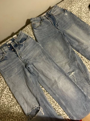 Två ljusblå jeans med slitningar - Säljer två par ljusblå jeans med snygga slitningar vid knäna och fransade detaljer längst ner. Båda har klassisk femficksdesign, hög midja och raka ben. Perfekt för dig som gillar en chill och trendig look med vintage-vibe.