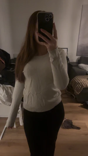 Kräm Vit stickad tröja med rund hals - Säljer en enkel och fräsch vit stickad tröja med rund hals och långa ärmar. Tröjan har ribbade muddar vid ärmslut och nederkant, vilket ger en snygg och clean look. Perfekt att matcha med jeans eller kjol för en chill stil.