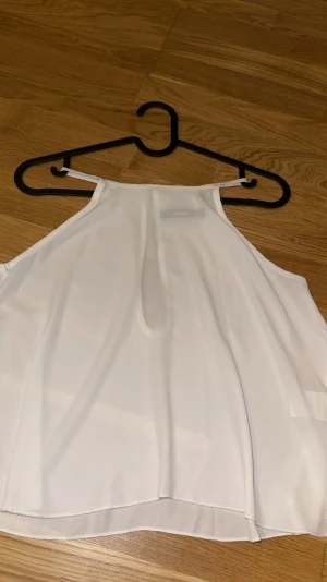 Vit ärmlös linnetopp från Bik Bok - Säljer en stilren vit linnetopp från Bik Bok i storlek S. Toppen är ärmlös med smala axelband och har en flowy, lätt transparent look. Materialet känns mjukt och svalt, perfekt för varma dagar. Enkel design med rundad hals och rak passform.