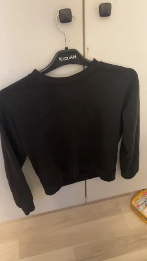 Svart croppad tröja - Svart croppad tröja från med rund hals och långa ärmar. Enkel och stilren design som passar perfekt till jeans eller kjol. Mjuk och skön kvalitet, perfekt för dig som gillar en clean look.