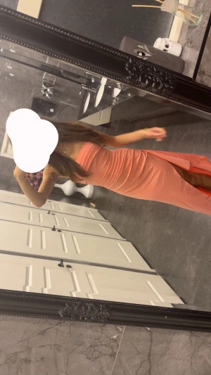 Lång korallrosa klänning med slits - Säljer en snygg axelbandslös lång klänning i korallrosa nyans. Har använts 1 gång. Klänningen har en figurnära passform och en hög slits på ena sidan som ger en extra touch. Perfekt för dig som vill sticka ut med en enkel men elegant look.