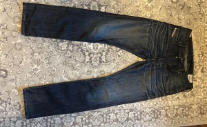 Diesel Krooley jeans mörkblå W30 L32 - Säljer ett par snygga Diesel Krooley jeans i mörkblå tvätt. Klassisk femficksmodell med raka ben. Jeans i bomull med snygga detaljer och Diesel Industry-logga på myntfickan. Perfekta för dig som gillar en stilren look.