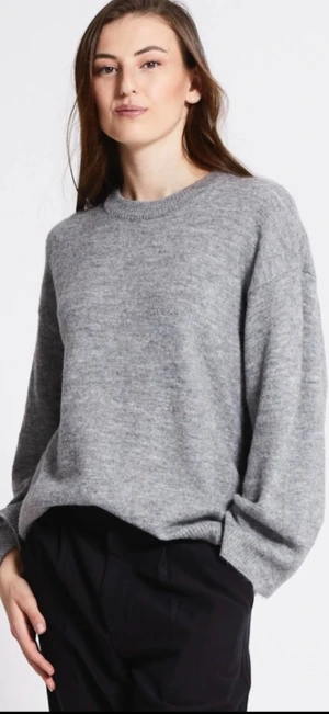 Grå stickad tröja med rund hals - Enkel och stilren grå stickad tröja med rund halsringning och avslappnad passform. Perfekt för lager-på-lager och funkar till både jeans och kostymbyxor. Mjuk och skön känsla tack vare det stickade materialet. Långärmad modell.
