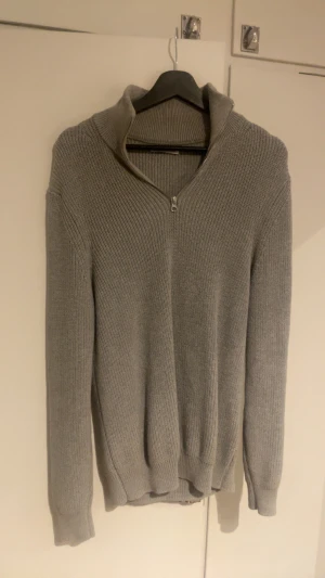 Grå stickad half zip-tröja från Zara - Säljer en grå stickad tröja från Zara i storlek M. Tröjan har en ribbad struktur, lång ärm och en snygg krage med half zip-dragkedja framtill. Perfekt för dig som gillar stilrena och enkla plagg. Storlek M, hör gena av er vid frågor eller funderingar😁pris kan diskuteras vid snabbaffär!