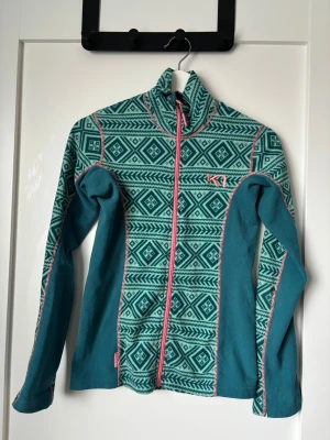 Fleece från Kari Traa XS - Säljer en snygg turkos och mörkgrön fleecejacka från Kari Traa i storlek XS. Är i bra skick men en liten reva längst ner på ena armen (se sista bilden). Perfekt o ha under jacka för extra lager!