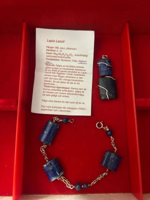 Lapis Lazuli armband och hänge - Unikt set med armband och hänge i djupblå lapis lazuli och äkta silver. Armbandet har cylinderformade stenar och små runda pärlor, ihopkopplade med tvinnade länkar. Hänget består av två lapis lazuli-stenar omslutna av silvertråd. Perfekt för dig som gillar ädelstenar och coola accessoarer.
