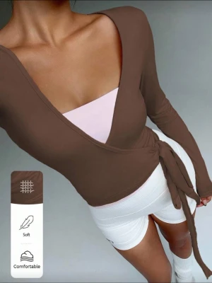 Brun omlottopp med knyt och v-ringning - Säljer en brun och vit omlottopp med lång ärm och djup v-ringning. Toppen har snygg knytning i sidan och är croppad i modellen. Materialet är mjukt och stretchigt, perfekt för dig som gillar bekväma och stilrena plagg. Passar dig som vill ha en enkel men trendig look.