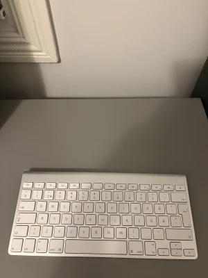Apple Magic Keyboard/tagnetbord - Snyggt Apple magic Keyboard i aluminium och vit design. Tangenterna är i gott skick och alla funktioner syns tydligt. Perfekt för Mac eller iPad. Inga synliga repor eller skador, ser välvårdad ut. Trådlös anslutning för smidig användning.