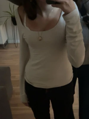 Smuts-vit  långärmad topp från Bik Bok - Säljer en vit långärmad topp från Bik Bok i storlek XS. Toppen har en snygg, tight passform med bredare rundad halsringning och är tillverkad i mjukt bomullsmaterial. Perfekt att styla med jeans eller kjol för en enkel och clean look.