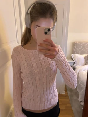 Ljusrosa kabelstickad tröja Polo Ralph Lauren - Supersöt ljusrosa kabelstickad tröja från Polo Ralph Lauren i mjuk pima bomull. Tröjan har rund halsringning, lång ärm och klassisk passform. Köpt för flera år sedan och säljs inte längre. Unik!