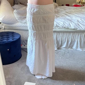 Vit långkjol med volangdetaljer - Supersöt vit långkjol med flera volangpartier och broderade detaljer. Säljer då den tyvärr är för kort för mig nu💞💞