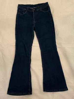 Mörkblå Bootcut Jeans - •Jeans i mörkblå tvätt med klassisk bootcut passform.  •Jeansen har fem fickor.  •Perfekt för dig som gillar retrovibbar och vill ha ett par jeans med lite extra sväng i benen.    •Köpt för ett par år sedan så säljs nog inte längre. Kommer inte ihåg vilken butik de är ifrån. Men de är köpta i Sverige.