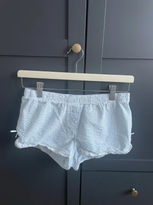 Ljusblå pyjamasshorts med rosetter  - Supergulliga ljusblå shorts med vita rosetter och  spetsdetaljer + elastisk midja. Storlek 158/164. Skriv vid intresse! 🩵