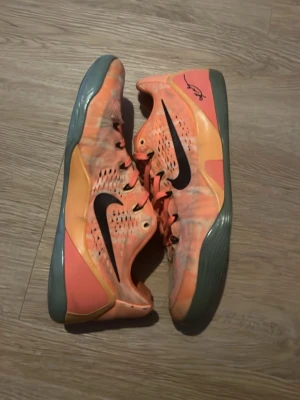Nike Kobe 9 peach jam orange sneakers - Säljer ett par Nike Kobe 9 sneakers i orange med svart swoosh och signatur på sidan. Nya kostar 40 000 tusen kronor mitt pris 2000. Skorna har mesh-överdel, snörning och grå sula. De har en låg siluett och coolt mönster i olika orange toner. Perfekta för dig som gillar basket och vill sticka ut. Äkta!!!!