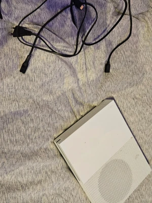 Xbox One S - Xbox One S i vitt utförande, med tillhörande strömkabel och HDMI-kabel. Konsolen har några mindre ytliga märken men ser överlag ut att vara i gott skick. Perfekt för gaming och streaming. Levereras utan handkontroll. Har två stycken. Hör av dig om due intresserad😊