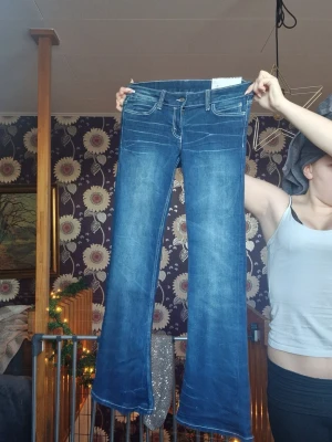 Blå bootcut jeans med broderade fickor - Säljer ett par blå bootcut jeans från Cheap monday med snygga vita broderier på bakfickorna. Jeansen har klassisk femficksdesign, kontrastsömmar och är tillverkade i jeansmaterial. Perfekt för dig som gillar detaljer och vill sticka ut lite extra. Dyra pgr av att dem e helt nya