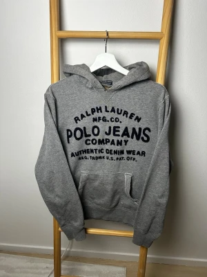 Grå Ralph lauren hoodie | S  - Ralph Lauren ”polo jeans” hoodie | bra skick men defekter förekommer (se bilder). Inget som påverkar helhetsintrycket | undrar du över något tveka då inte på att höra av dig ⚜️|